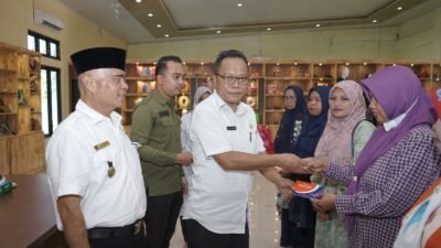 Asisten Perekonomian dan Pembangunan Oktoni Eriyanto, menyerahkan Buku Tabungan Dana Pinjaman Bergulir kepada Pelaku Usahan Mikro di Aula Gedung Dekranasda Kabupaten Asahan. (Humas)