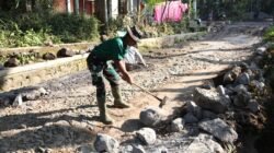 Satgas TMMD ke-129 Kodim 0821/Lumajang Maksimalkan Pembuatan Parit, Prada Muhamad Fathur Pecah Batu untuk Perkuat Drainase
