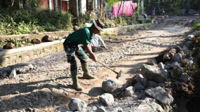 Satgas TMMD ke-129 Kodim 0821/Lumajang Maksimalkan Pembuatan Parit, Prada Muhamad Fathur Pecah Batu untuk Perkuat Drainase